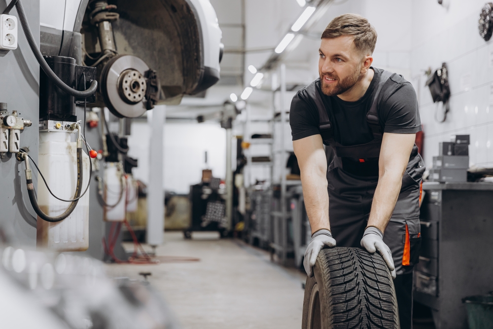 Happy,Smiling,Car,Mechanic,Working,In,Garage,And,Changing,Wheel